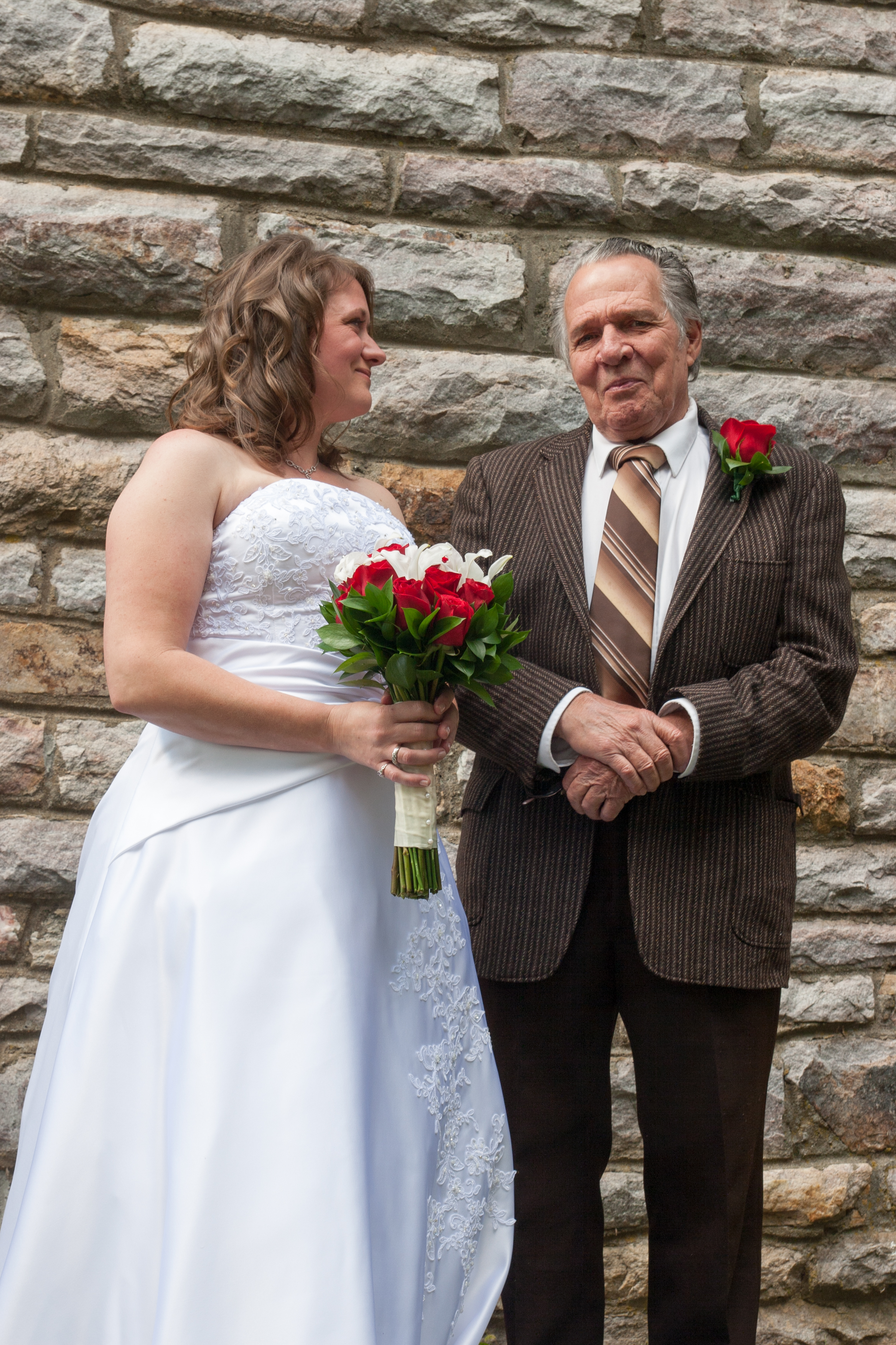 Bride and father with stone wall background