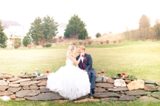 winter wedding couple sit on stone wall