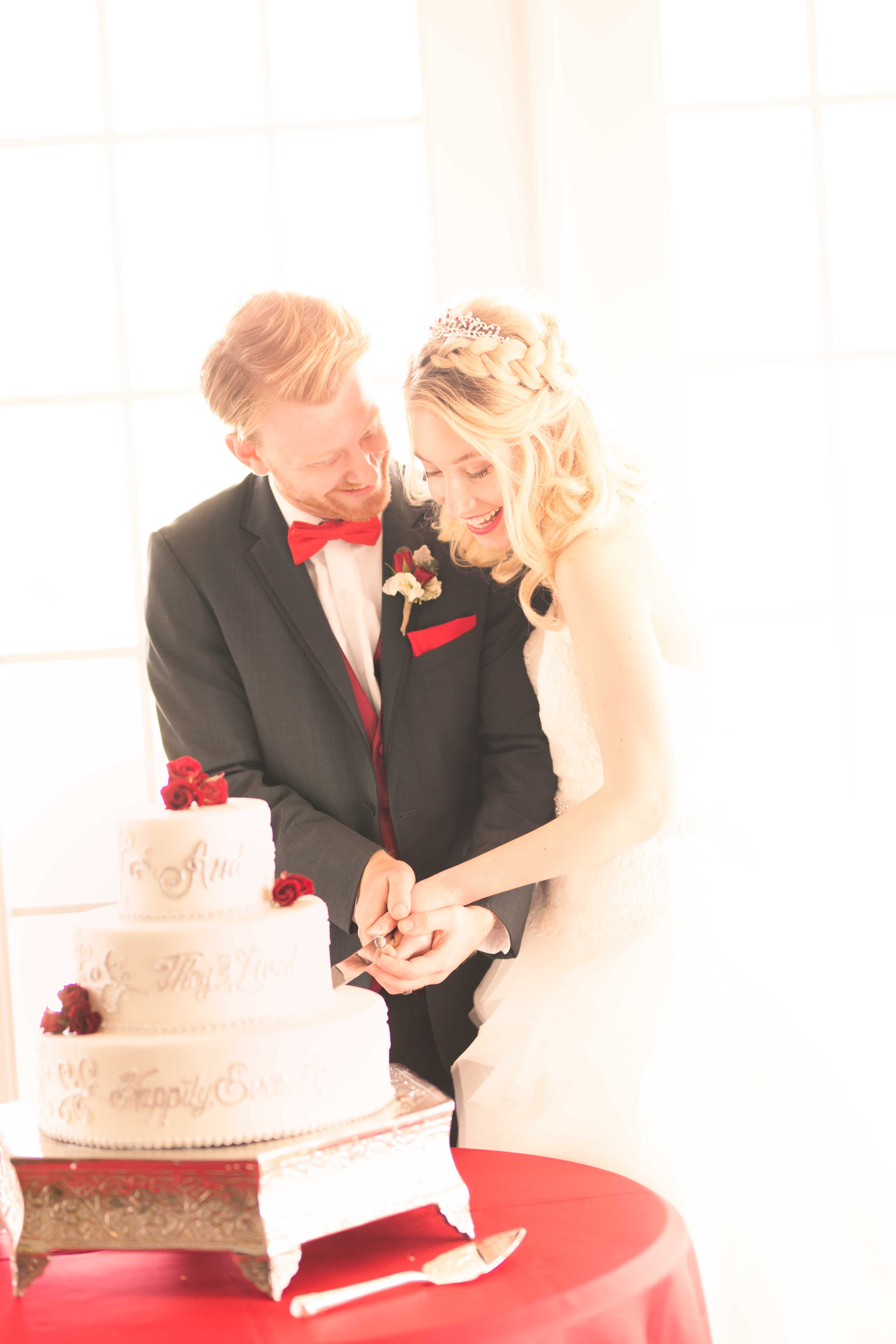 red winter wedding couple cut cake