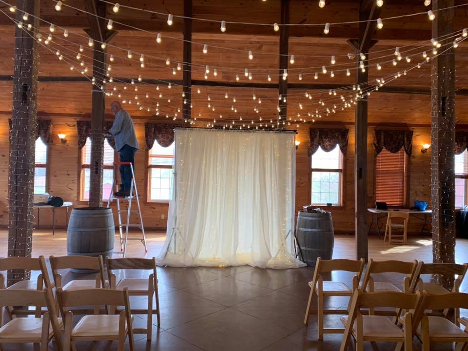 String lighting being hung above a dance floor for a wedding setup